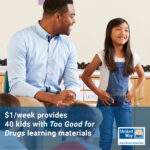 A young Asian girl wearing overalls stands at the front of a classroom, next to her teacher - a black male - who is sitting on a chair; blue box with text across the bottom: $1/week provides 40 kids with "Too Good for Drugs" learning materials