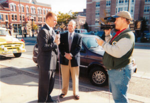 WXOW reporter Chris Stauffer and camera operator Kevin Millard interview La Crosse Tribune Editor Rusty Cunningham in front of the La Crosse Center at the October 11, 2001 "United We Stand" event.