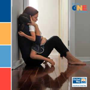 Mother and young daughter sitting on hallway floor, embracing.